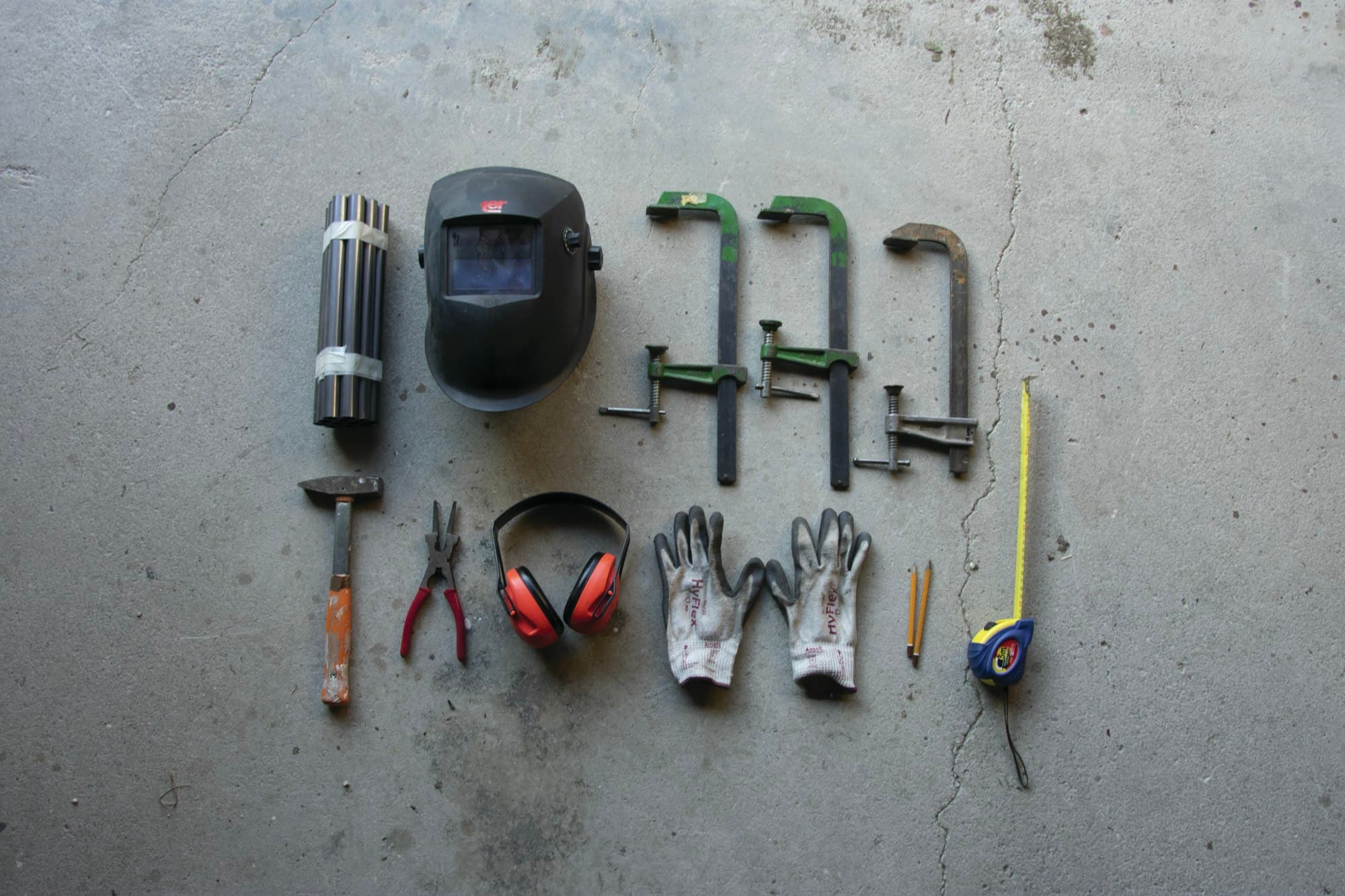 An assortment of hand tools laid out on a grey concrete floor.