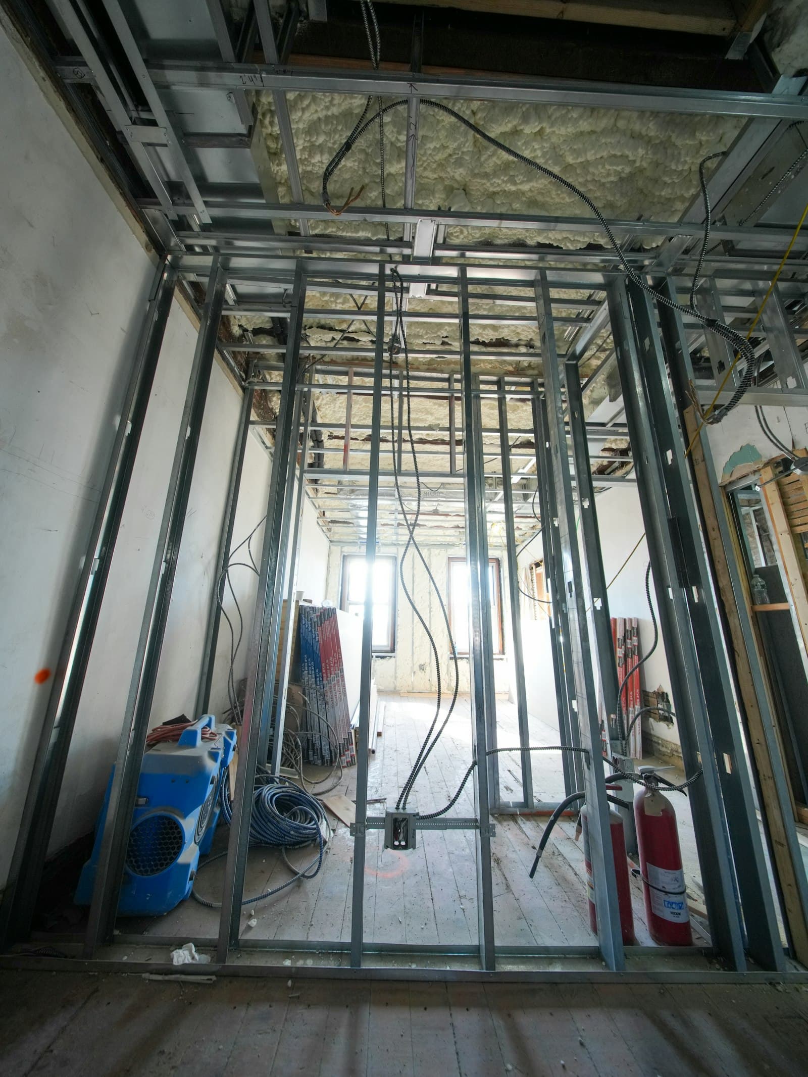An interior stripped back to metal studs with electrical wiring running through them.