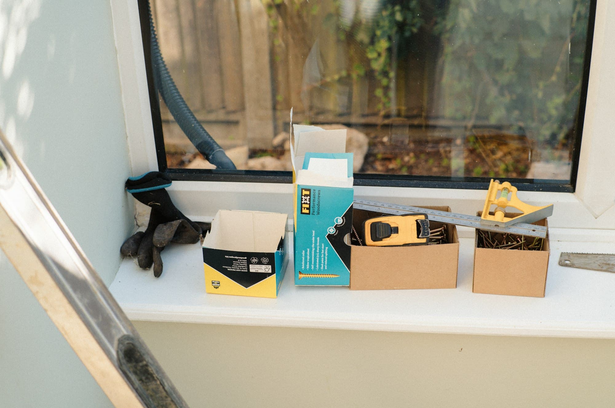 Work gloves and hand tools laid out on a white windowsill.