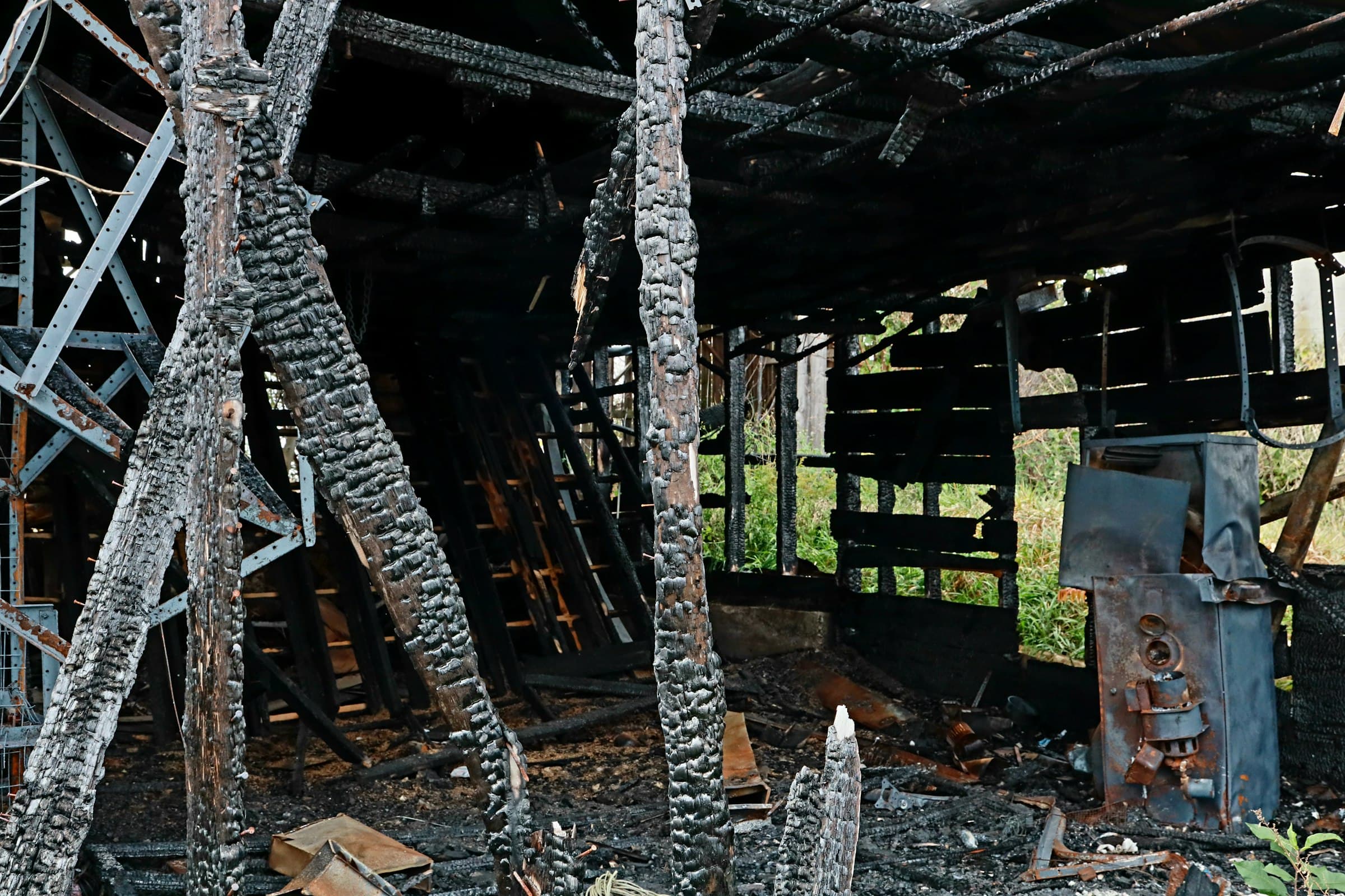 The inside of a burnt wooden structure, its beams blackened and cracked by fire.